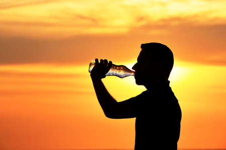 Man in drinking water at the sunset.の写真素材