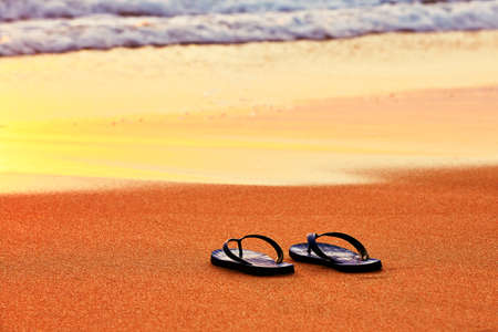 Flip flops on the beach at sunsetの写真素材