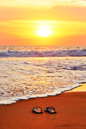 Flip flops on the beach at sunsetの写真素材