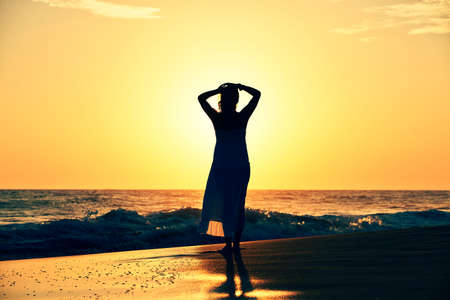 Pretty woman at sunset on the beach の写真素材