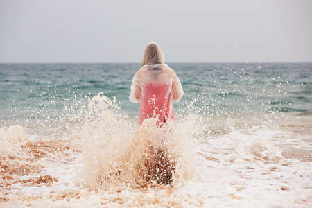 Young woman on the beach in heavy rainの写真素材