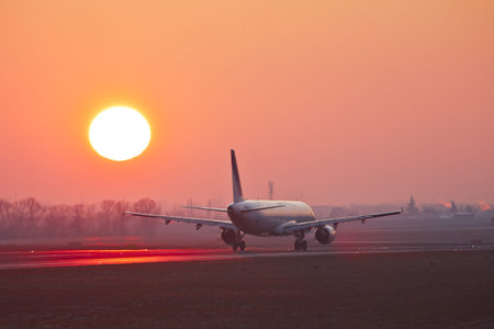 Airplane is taking off at the sunset.