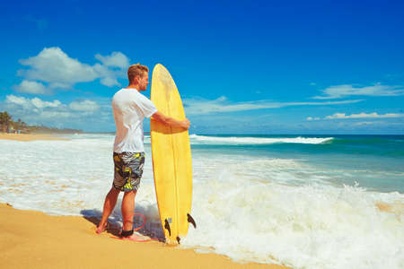 Man with surfboard on the beach at sunset.の写真素材