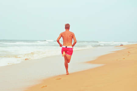Young man is running on the beachの写真素材