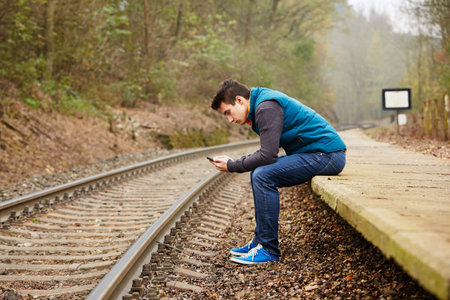 Young man is waiting on the platform rural railway stationの写真素材