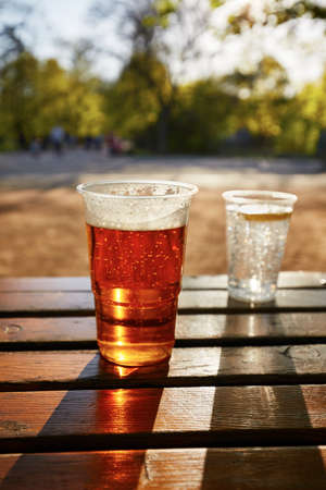 Cups of beer and water in the garden restaurantの写真素材