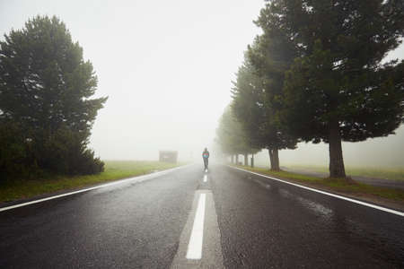 Lonely man is walking in mysterious fogの写真素材