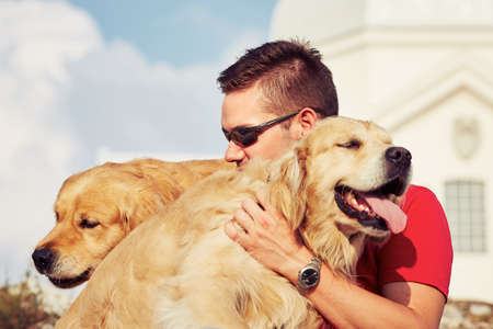 Young man with his dogs (golden retriever).の写真素材