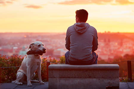 Young man with his dog at the sunrise.の写真素材