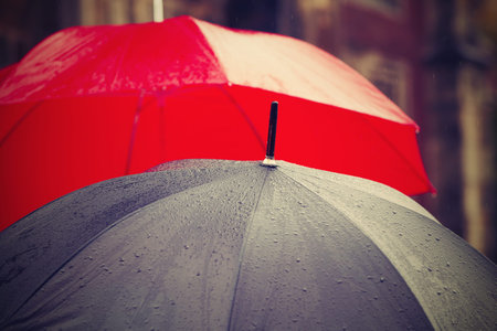 People with umbrellas in rain on the street - selective focusの写真素材