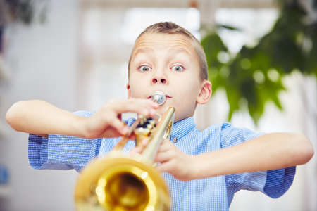 Little boy is playing the trumpet at homeの写真素材