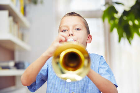 Little boy is playing the trumpet at homeの写真素材