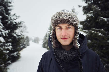 Portrait of young man outdoors in winter under snowstormの写真素材