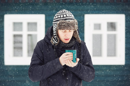 Portrait of young man outdoors in winter under snowstormの写真素材