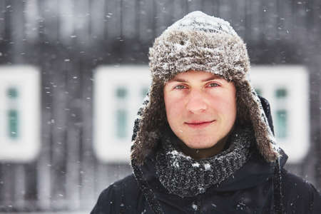 Portrait of young man outdoors in winter under snowstormの写真素材