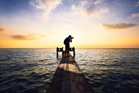 Young photographer is taking photos at the sunset.