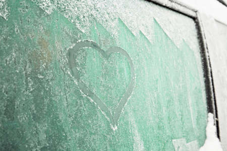 Heart symbol on frozen window of the carの写真素材