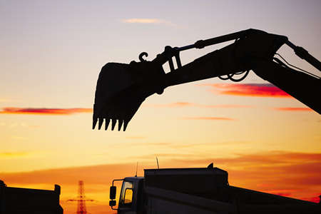 Silhouette of the backhoe in the building siteの写真素材