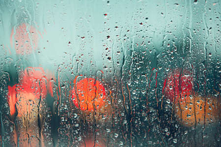 Heavy rain. Raindrop on the window of the car. Abstract blur bokeh of traffic and car light.の写真素材