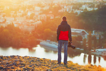 Young photographer is enjoying sun. Photographer with mirror camera is ready to take sunrise pictures.の写真素材