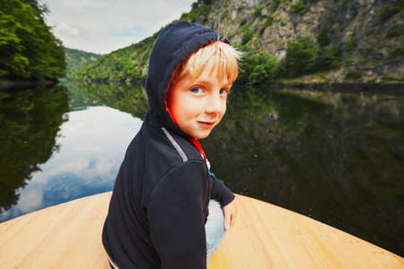 Little traveler on the river. Boy is sitting on the boat.の写真素材