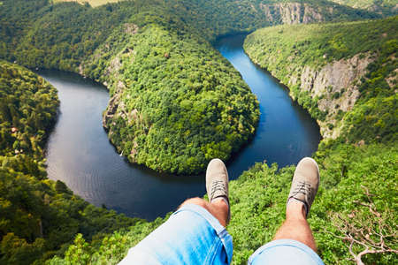 Feet of the young man (traveler) in sneakers on the background of amazing landscape with Vltava river in Czech Republic.の写真素材