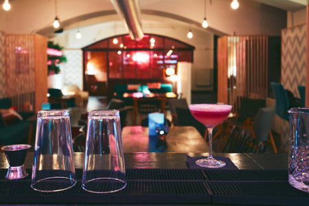 Interior of the small night bar in downtown. Red coctail on the bar counter - selective focus on the...