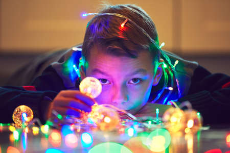 Christmas surprise is coming. Cute little boy playing with magic Christmas light at the home.の写真素材