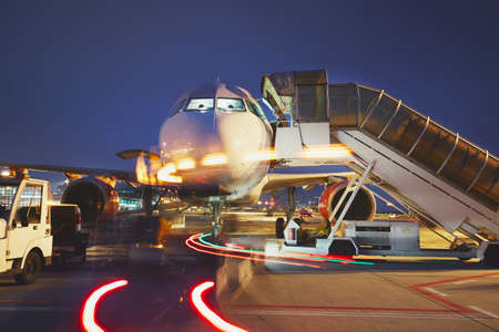 Busy airport in the night. Preparation of the airplane before flight.の写真素材