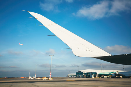 Daily life at the international airport. Detail of the wing of the airplane and second airplane is...