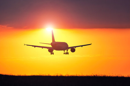 Airplane landing at the airport during amazing sunset.の写真素材