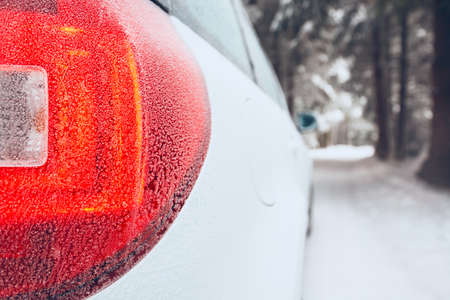 Detail of the stop light. White car on winter road.の写真素材