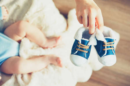 Boots for baby. Mother holding shoes her little boy.の写真素材