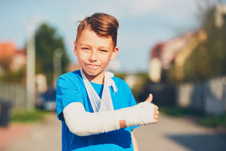 Mischievous boy with broken hand injured after accident showing OK signの写真素材