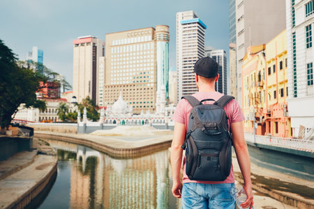 Young tourist watching on modern city with high-rise and old traditional buildings and Masjid Jamek Mosque in Kuala Lumpurの写真素材