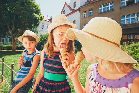 Summer day in the city. Cute siblings with hats eating big ice cream in the park.の写真素材