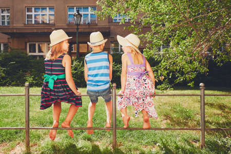 Summer day in the city. The three siblings sit on the railing and relax.の写真素材