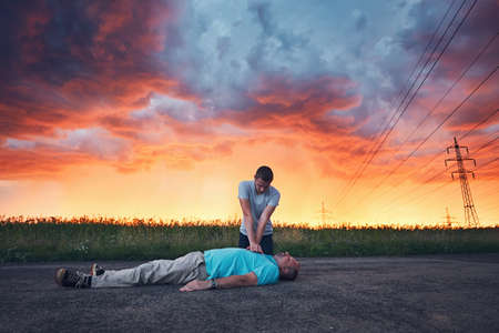 Dramatic resuscitation on the road during storm at the spectacular colorful sunset. Themes rescue, help and hope.の写真素材