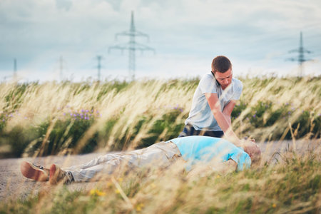 Young man calling for Emergency medical service. Dramatic resuscitation on the rural road. Themes rescue, help and hope.の写真素材