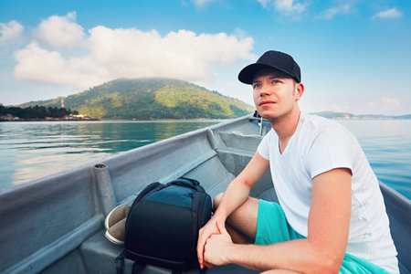 Side view of young man while traveling in boat on sea against tropical islands and blue sky.