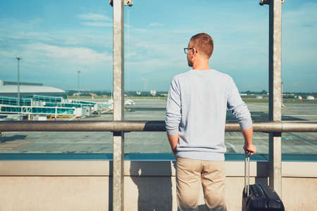 Man traveling by airplane. Young passenger waiting at the airport for a delayed flight.の写真素材