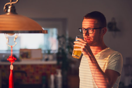 Morning time at home. Pensive man drinking juice in the kitchen.