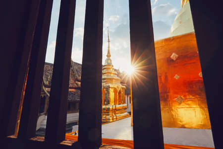 View from the window of the buddhist Phra Singh Temple at the sunset. Tourists favorite landmark in downtown Chiang Mai in Thailand.の写真素材