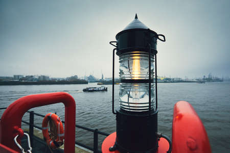 Beacon against freight ship and harbor. Gloomy and cold day in Hamburg, Germany の写真素材