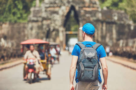 Tourist in the ancient city. Young man with backpack coming to ancient monuments. Siem Reap, Cambodiaの写真素材