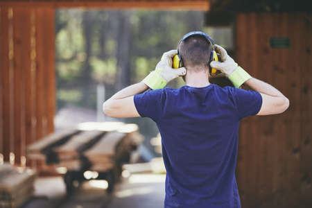 Man working in sawmill. Rear view of the worker with headset. の写真素材