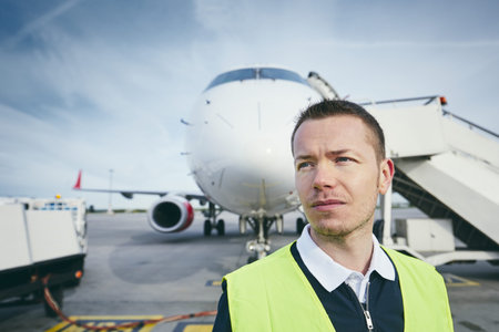 Member ground crew worker at the airport in front of the airplane. 