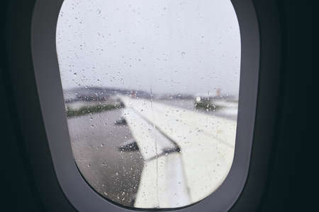 Close-up of airplane window during rain. Selective focus on raindrops. の写真素材