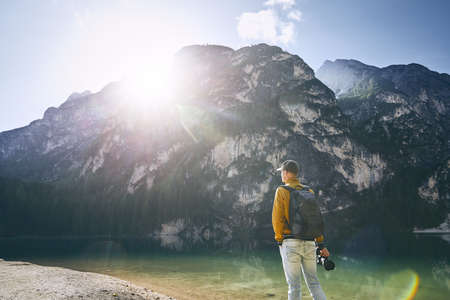 Young photographer holding camera against Lake Braies and mountains during sunrise. Dolomites, Italyの写真素材
