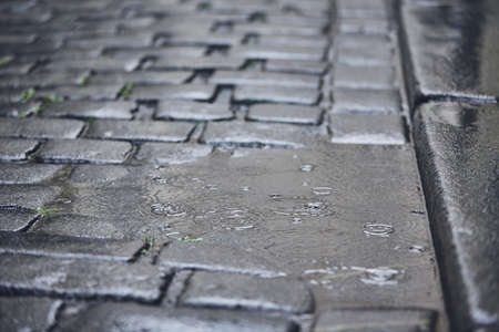 Puddle on road in rain. Full frame shot of cobblestone street.の写真素材